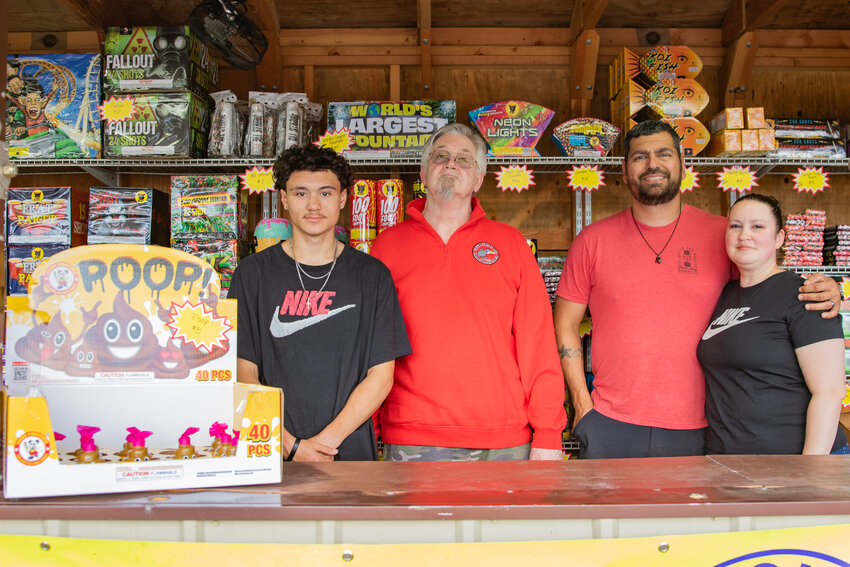 From the right, volunteers Amanda and Anthony Soto, Bob Buswell and Tylor Vasquez pose for a photo inside the Toledo Lions Club fireworks stand at the Toledo Market Fresh parking lot on Saturday, June 28.