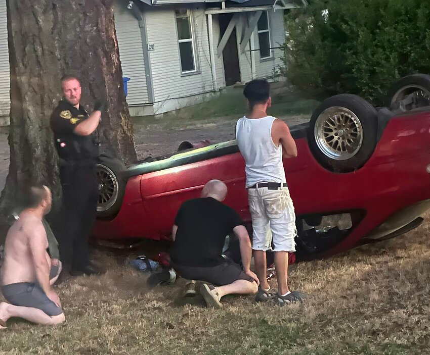 Thurston County Commissioner Wayne Fournier, crouched at center, assists at the scene of a rollover crash in Centralia on Monday in this photo he provided to The Chronicle.