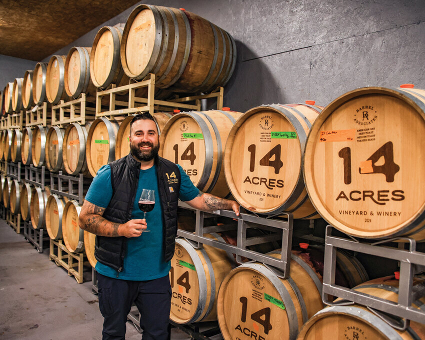 Owner and winemaker of 14 Acres Vineyard and Winery David Regan stands in front of a wide variety of wines in oak barrels with a glass in hand on Tuesday, July 8.
