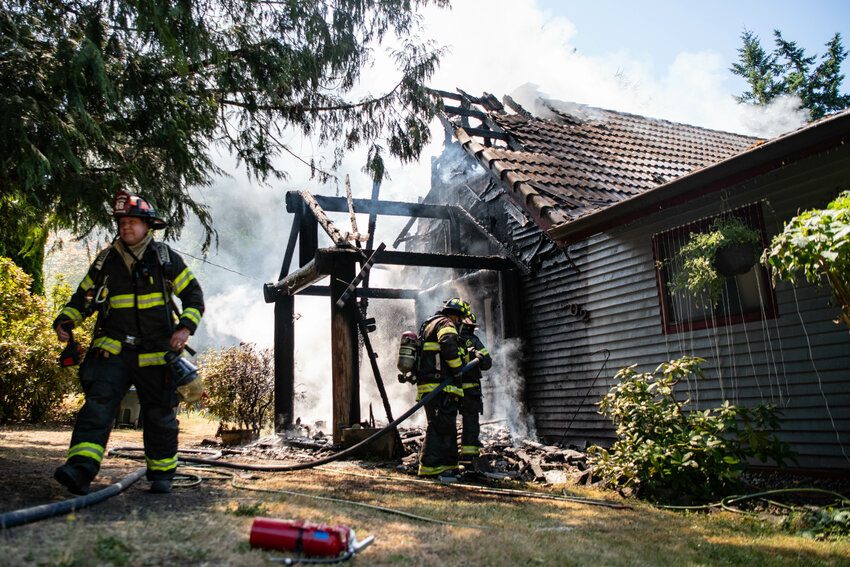 Firefighters use a hose while the Riverside Fire Authority and Chehalis Fire Department work to extinguish a house fire on Seminary Hill Road outside of Centralia on Wednesday, July 16.