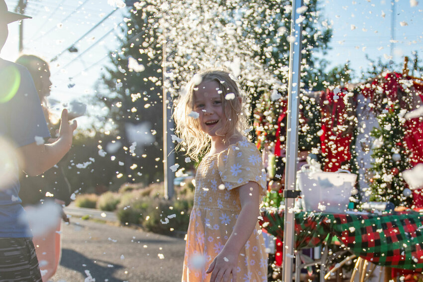 Poppy Moseley smiles as fake snow flurries at the Centralia Downtown Association&rsquo;s Christmas In July Block Party on Wednesday, July 24, 2024.