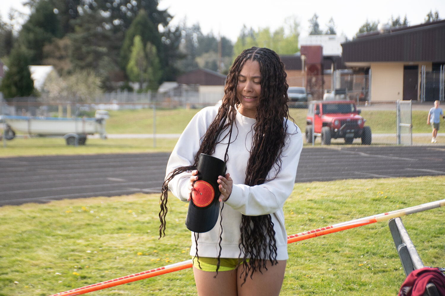 Rainier senior Janess Blackburn celebrates her school discus record by breaking a vinyl record at practice on Thursday, April 24.