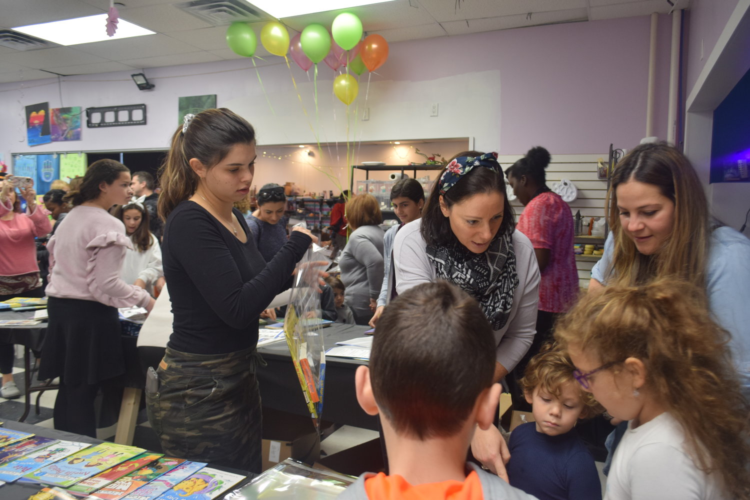 Volunteers Susanna Horowitz, left and Adi Carucci, center, helped a family wrap books at the Hindi’s Libraries Gobble Gobble Book Fest on Nov. 17.