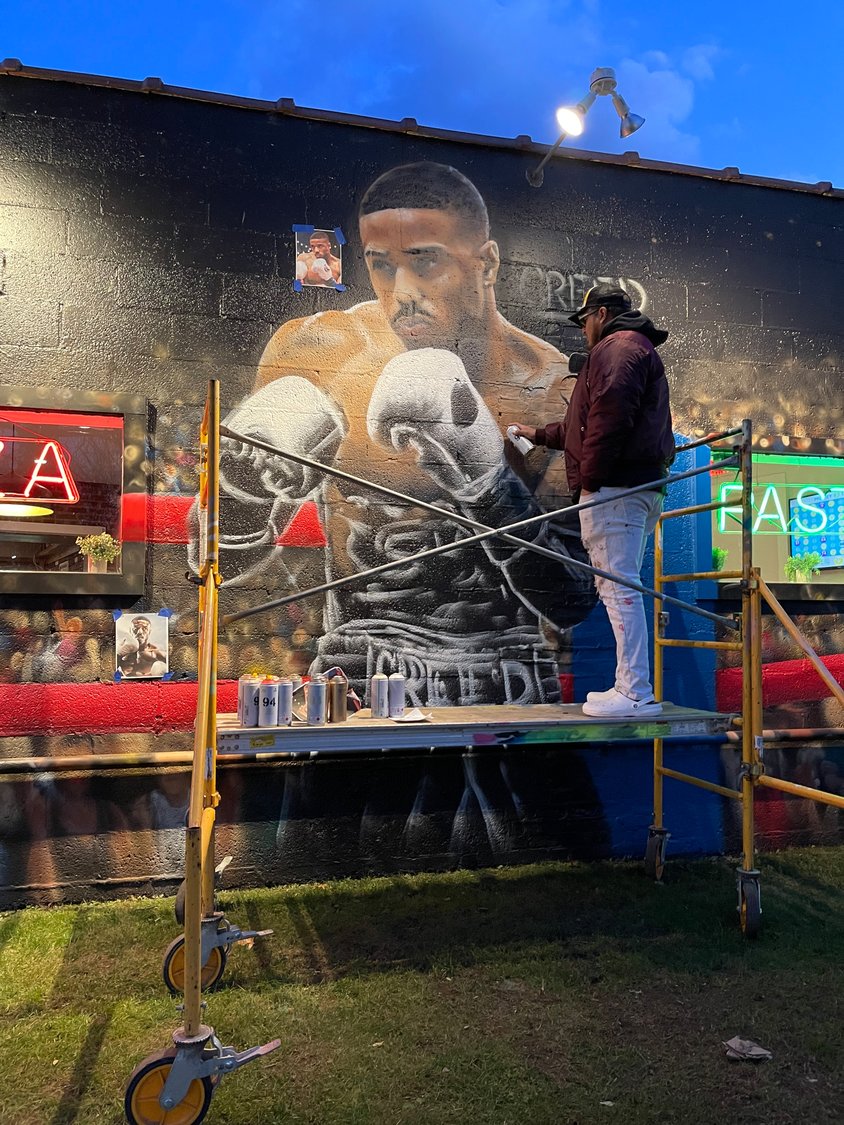 Street artist Efren Andaluz said his mural, “The Passing of the Torch,” at Pietro’s Pizzeria on East Meadow Avenue in East Meadow, is a tribute to the “Rocky” movies, with a twist — Rocky is in the ring with his protégé, Adonis Creed.