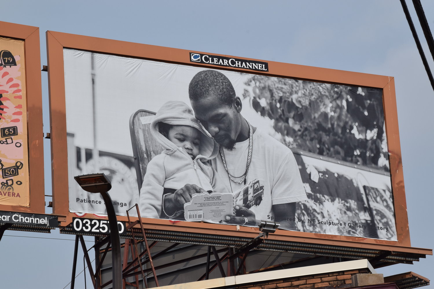 Photographer Patience Zalanga's billboard is of a moment she captured of a father reading to his son on a bench at George Floyd Square, a book he chose from the community's free library.(Photo by Jill Boogren)