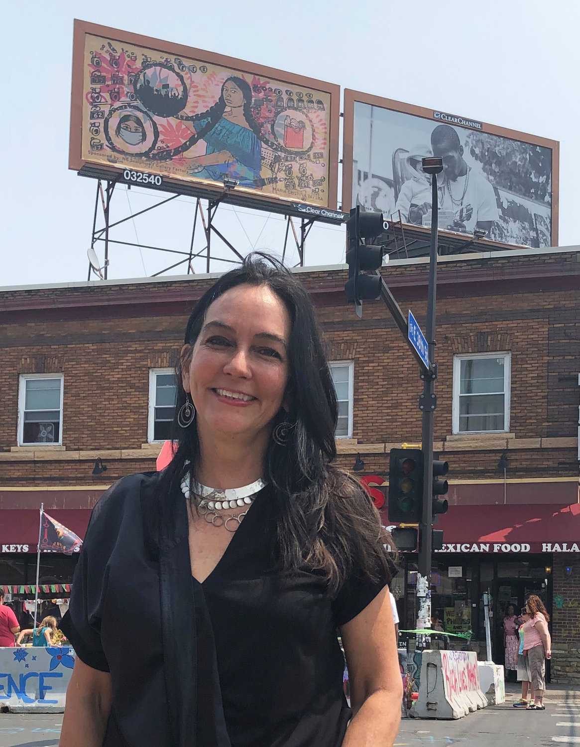 Tina Tavera stands with her billboard “La Conneccion” on the Cup Foods rooftop behind her. (Photo by Jill Boogren)