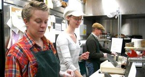 (l to r) Volunteers Alex Newby, Mikaila Dahlseng and Mel Seeland spend an evening at the Co-op cutting cheese. (Photo by Jan Willms)