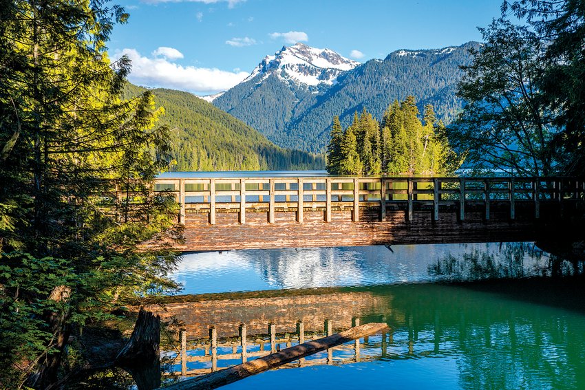 A bridge crosses over the water along a trail around Packwood Lake.