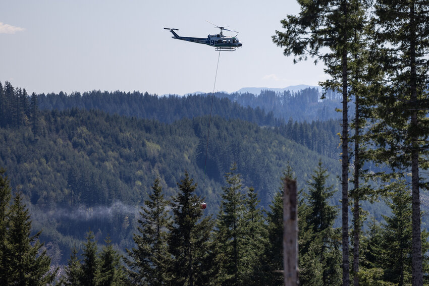 A helicopter flies to a drop point during a DNR aviation exercise in the Capitol State Forest on Wednesday, April 17.