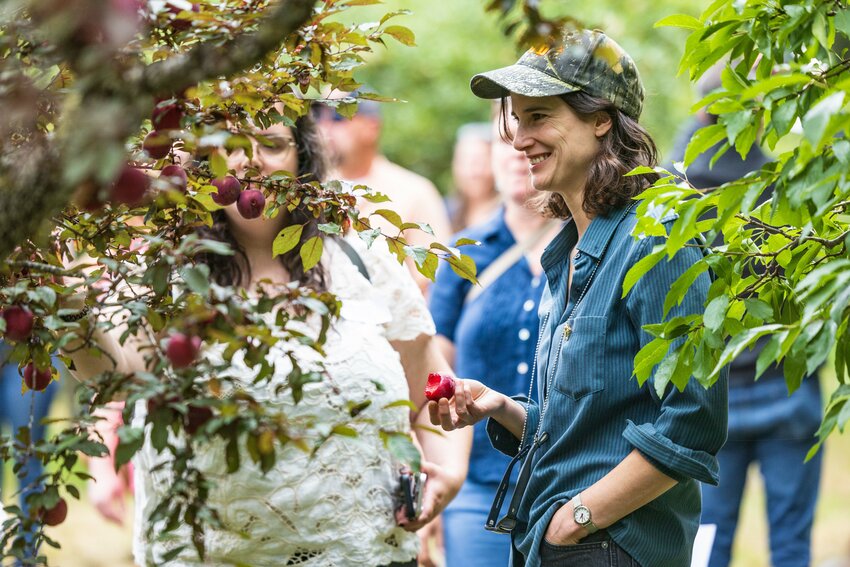 Congresswoman Marie Gluesenkamp Perez smiles while eating a freshly picked fruit at Raintree Nursery on a Lewis County Farm Bureau Tour on Wednesday, Aug. 14, 2024.