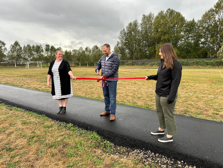 Columbia Elementary School Principal David Starkey cut the ribbon during a ceremony for its new asphalt track held on Wednesday, Sept. 25. Parent Teacher Association board members Katie Murdock (left) and Kellie Tooley fundraised proceeds for the running track.