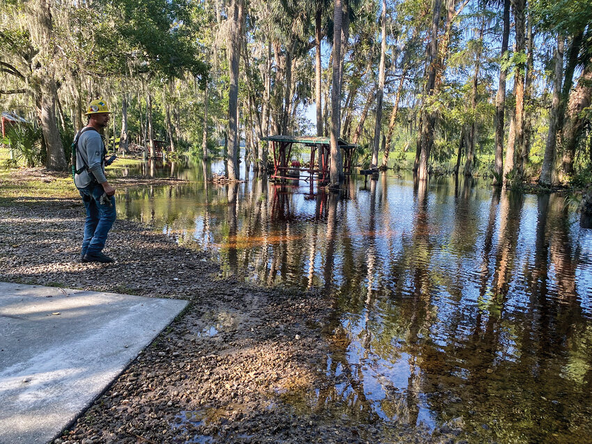 Clark Public Utilities crew members navigate flooded, swampy terrain near Orlando, Florida, while repairing power lines damaged by recent hurricanes. Though unaccustomed to the high water levels and dense vegetation, the Washington-based crews succeeded in replacing two poles and restoring power lines in these conditions.