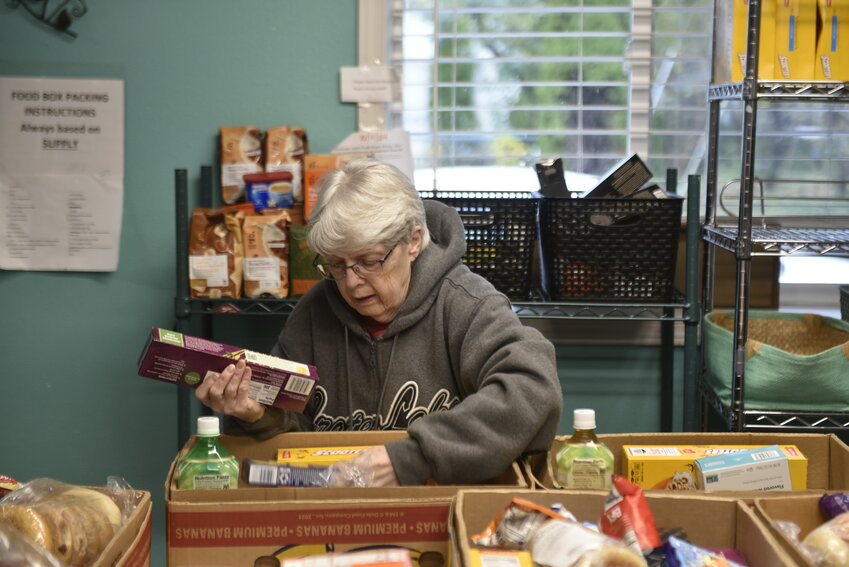 Nancy Darby, a food bank volunteer, organizes food items for pickup at the North County Community Food Bank. The organization is working to raise $8,000 to match a grant aimed at supporting its operations and food purchases.