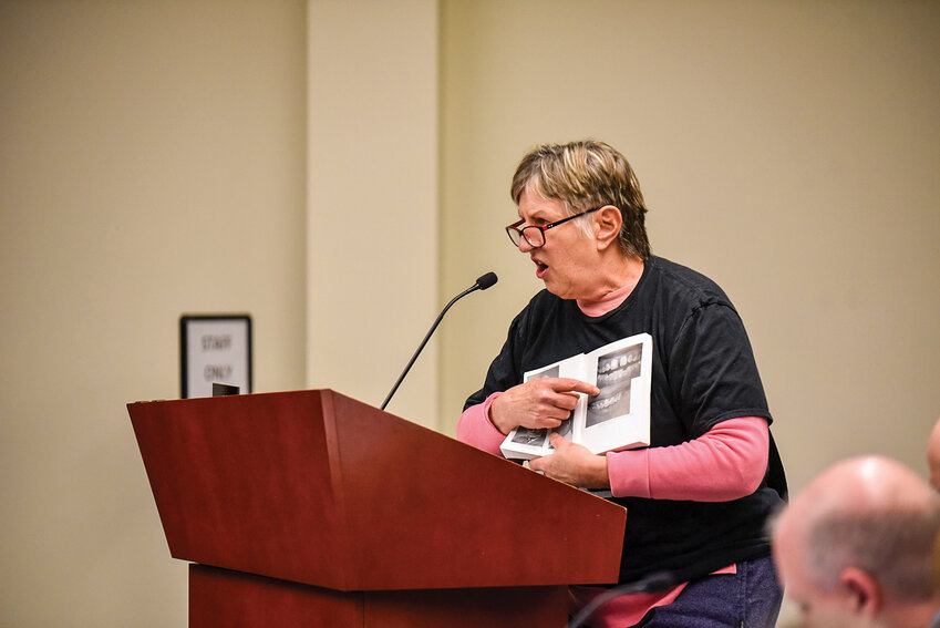 Wynn Grcich stands at the microphone during the public comment portion of the Battle Ground City Council meeting on Monday, Jan. 6. She held up a book she says links fluoride to brain damage, criticizing the council for continuing the practice of water fluoridation despite health concerns.