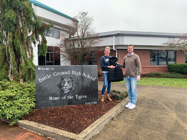 Attorney Colin Scott, founder of The Scott Law Firm, PLLC, holds a winter coat with Battle Ground High School Principal Heather Ichimura after a coat drive that The Scott Law Firm participated in to benefit Battle Ground High School students.