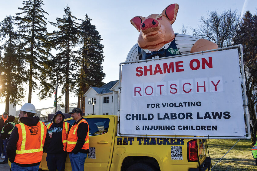 Members of Sheet Metal Workers Local Union 66 stand in front of a sign and inflatable pig balloon during a chilly morning on Wednesday, Jan. 22. Union workers spanning several local labor industries protested at the Port of Longview, when commissioners voted 2-1 to award a $44.6 million contract to Rotschy Inc., a Vancouver-based construction company with a history of labor violations.