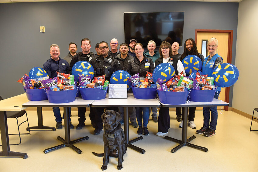 Battle Ground Police Department officers and Walmart staff pose together at BGPD headquarters, standing behind Game Day meal baskets provided in appreciation of the officers&rsquo; service.