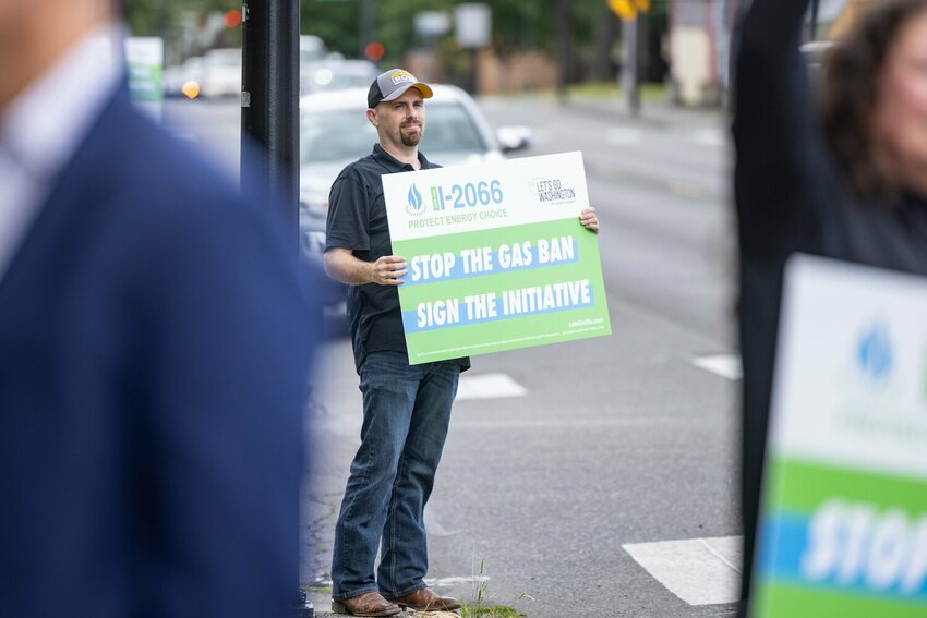 A supporter of Initiative 2066 holds a sign as cars drive by for a &ldquo;super signing&rdquo; event at Eubanks Glass in Centralia on Thursday, June 27.