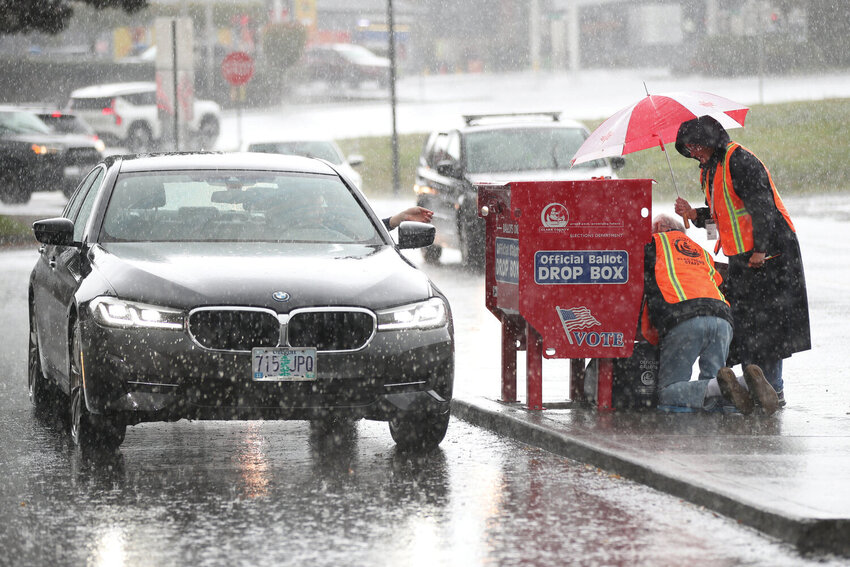 Elections workers collect ballots as voters drop them off at the Fisher's Landing Transit Center ballot drop box, which was replaced after a fire caused by an incendiary device, in Vancouver, Wash., Tuesday, Nov. 5, 2024.