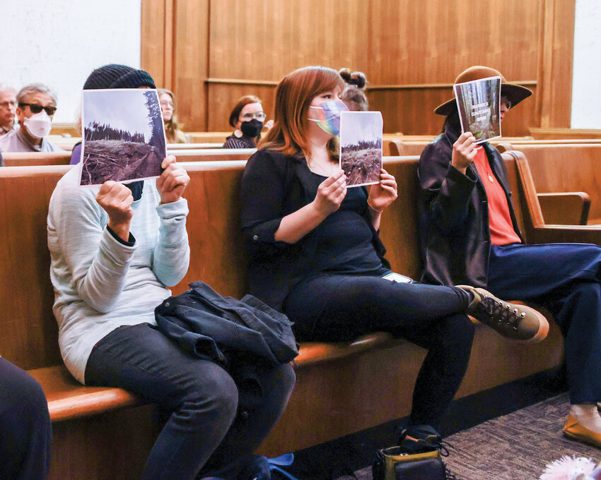 A group in attendance during a Wednesday, Feb. 26, court hearing between the Legacy Forest Defense Coalition and the Friends of Clark County and the Washington Department of Natural Resources held up photos showing the present state of the Dabbler timber sale harvesting.