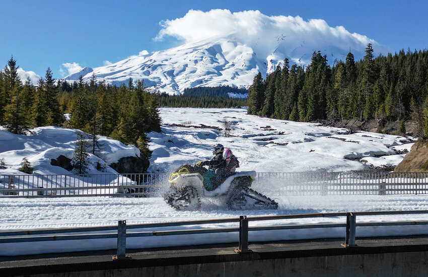 A tracked quad driver carrying a blind student crosses a bridge during the 2025 Mount St. Helens Trac Riders Washington Blind School Ride near Marble Mountain Snow Park in the Mount St. Helens National Volcanic Monument on Thursday, March 6.
