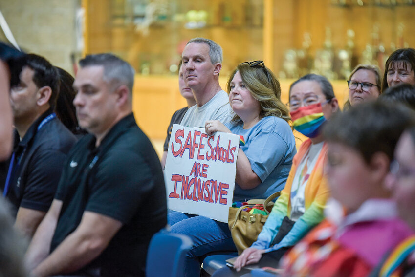 An attendee holds a sign reading "safe schools are inclusive" during a La Center School Board meeting held on Tuesday, March 25. Community members gathered to oppose the district's gender identity policy, which OSPI ruled as discriminatory.