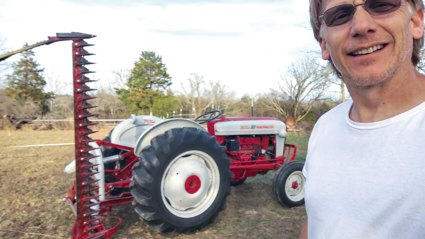 Country music artist and George Strait tribute singer Tim Hadler enjoys mowing with the old Ford tractor at the GUMI Camp USA site for veterans in Cedar Creek, Missouri.