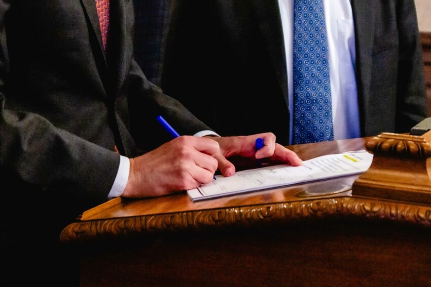 Gov. Bob Ferguson signs a bill on Friday, April 4, 2025. On Monday, he signed more legislation into law, including a bill to prohibit the sale of sodium nitrite. (Photo by Jacquelyn Jimenez Romero/Washington State Standard)