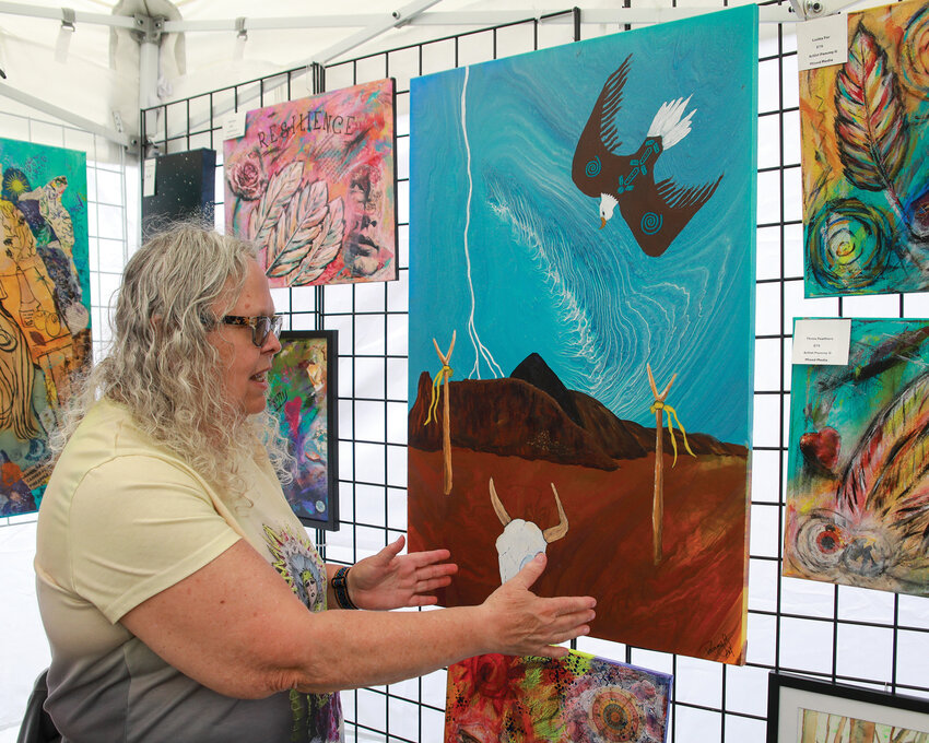 Pamela Grant, a painter, mixed media artist and more from Vancouver, explains her painting, &ldquo;Eastern Gate,&rdquo; while in attendance as a vendor at the second annual La Center Arts Fair at Holley Park on Saturday, May 10.