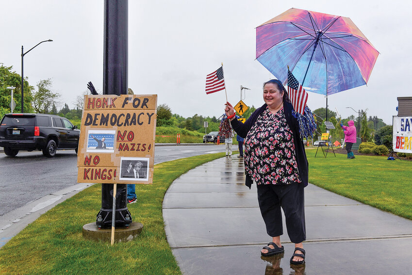 A protestor waves American flags next to a sign that reads "No Nazis, no kings" during a May 15, 2025 demonstration in Ridgefield.