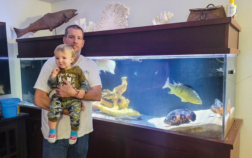 Battle Ground resident Rick Kaliszewski stands with his grandson in front of his 300-gallon fish tank on Thursday, May 22, after the family&rsquo;s fish recovered from a near-fatal water change incident he suspects was caused by a lack of quality in the city&rsquo;s water on Monday, May 19.