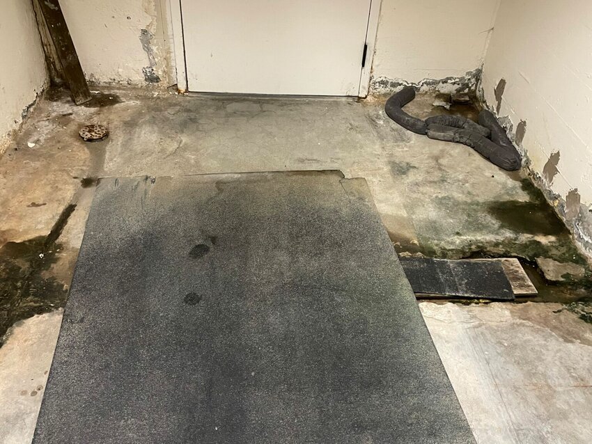 An underground tunnel connecting two Washington state legislative buildings is plagued by water leaks. This damaged concrete and pooled water is just outside the entrance to the House office building. Lawmakers earmarked $4 million in the 2025-27 capital budget to make repairs and install proper drainage. (Photo by Jerry Cornfield / Washington State Standard)