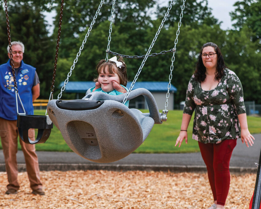 Haley Atwood pushes the new ADA swing for her daughter Charlotte at Holley Park in La Center after the ribbon-cutting ceremony for the new swing on Friday, June 13.
