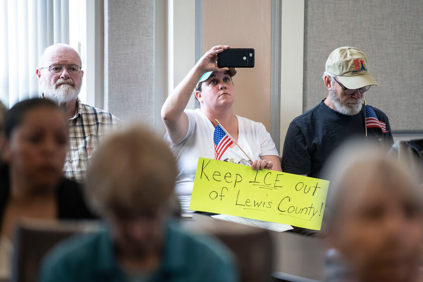Liz Oxford holds a sign and takes a video of public comment during the Tuesday, July 8, business meeting at the Lewis County Courthouse in Chehalis.