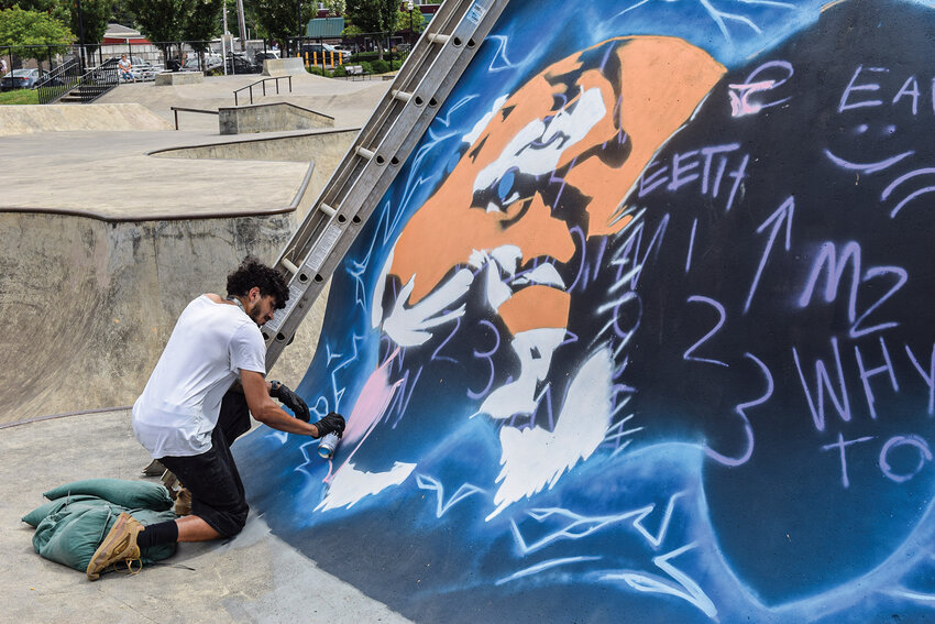 Will Sykes paints the first tiger on the outer wall of the skate dome on Thursday, July 10. The mural, titled "Tiger Pride," features five tigers surrounded by lightning to symbolize strength and unity.
