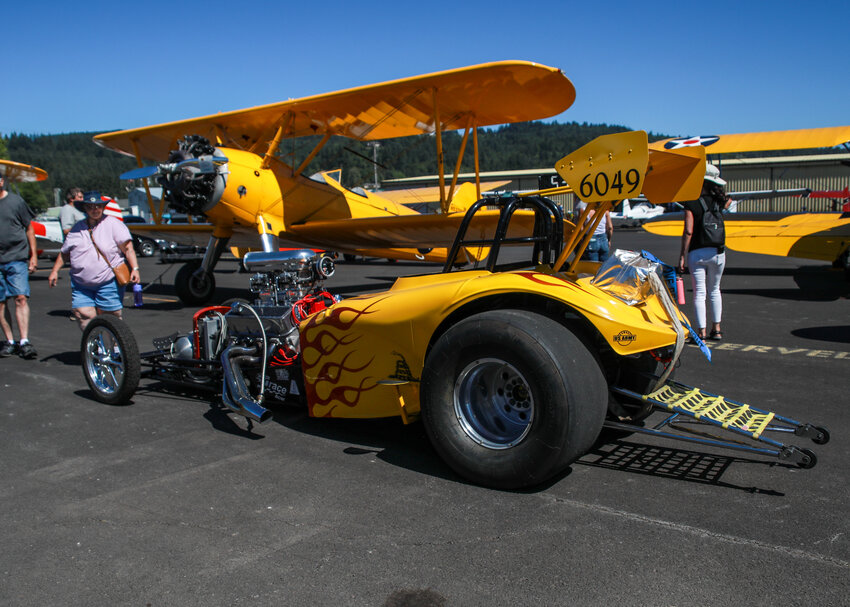 A yellow dragster is parked in front of multiple yellow aircraft during Cascade Air&rsquo;s fly-in and car show that featured the Puget Sound Antique Airplane Club and Unique Tin Car Club at the Southwest Washington Regional Airport in Kelso on Sunday, July 13.