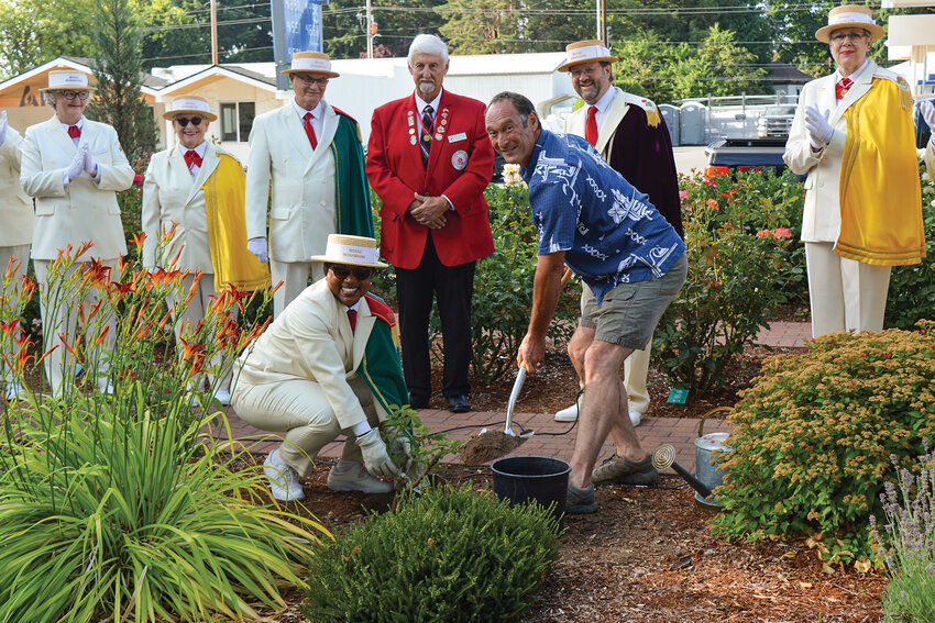 Tyler Castle digs into the soil with members of the Royal Rosarians during the annual rose planting ceremony at Central Park on Saturday, July 19. Castle was honored as Battle Ground&rsquo;s 2024 Citizen of the Year for his volunteer work across Clark County.