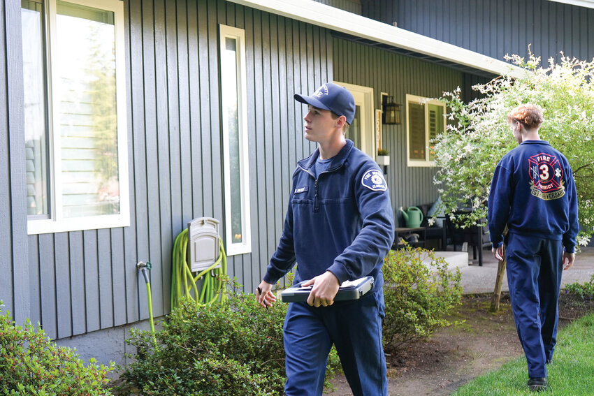 Fire risk specialists Brayden Brault (left) and Ashton Fergason inspect the area outside a home in July. The team spearheads Fire District 3's annual summer effort to assess fire risks and help homeowners assess potential wildfire mitigation.
