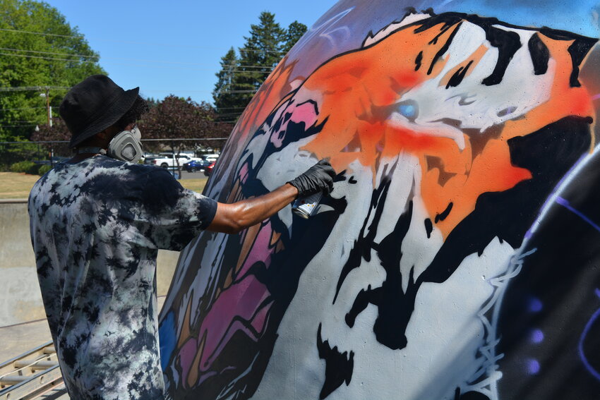 Muralist Will Sykes outlines whiskers with black spray paint on the third tiger of his mural at Battle Ground Skate &amp; Bike Park on Thursday, July 17. The artist has completed three of five tigers in the &ldquo;Tiger Pride&rdquo; piece, which is now past its halfway point.