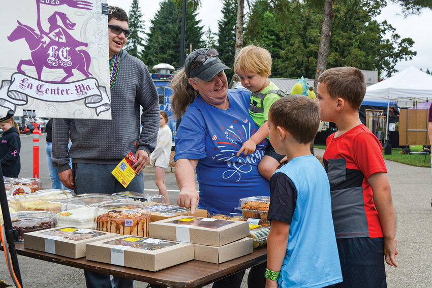 Irene Small and Cannon Ashton, seen in green, pick out a cake after they won the cake walk. The musical chairs-style contest was held at 10 a.m. Saturday, July 26, on the main stage at Holley Park during La Center&rsquo;s Our Days Steamboat Celebration.