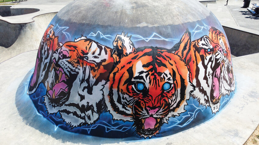 A mural wraps across the curved dome at Battle Ground Skate &amp; Bike Park at Fairgrounds Park with six tiger heads, lightning, and a blue aura. Will Sykes completed the mural on Thursday, July 24, after more than two weeks of painting.