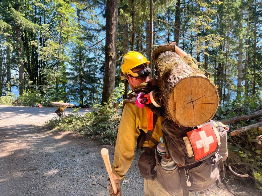 A firefighter moves hazard fuel while working on the Bear Gulch fire this summer. Many in the wildland fire community believe the leadership team managing the fire sent crews into an ambush by federal immigration agents. (Facebook/Bear Gulch Fire 2025)