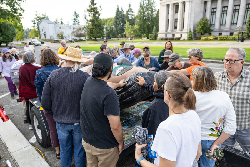 Attendees place their hands on the &ldquo;Bear-Becomes-Man&rdquo; totem pole during the &ldquo;Xaahl and the Way of the Masks&rdquo; event at the Washington state Capitol in Olympia on Monday, Sept. 8.