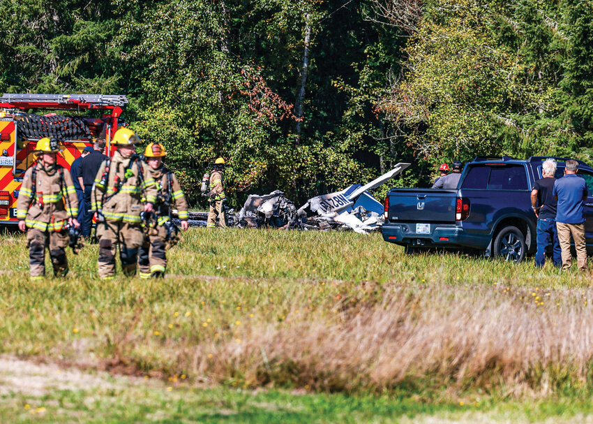 First responders walk away from a small plane that crashed and was fully engulfed in flames shortly after 1 p.m., Friday, Sept. 26, at Goheen Airport, a public use airfield with a grass runway north of Battle Ground.