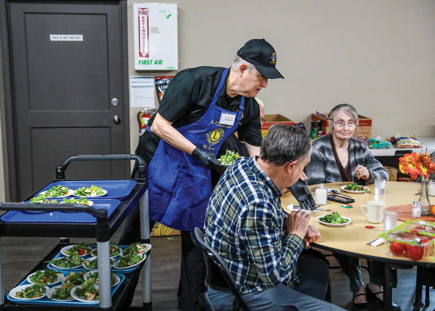 La Center Lions Club volunteer Lance Ebarb delivers salad to a table of senior citizens during the first La Center Lions Senior Lunch on Thursday, Oct. 2, after the Meals on Wheels People announced service changes for satellite locations in Clark County due to federal funding losses leading to budget cuts.