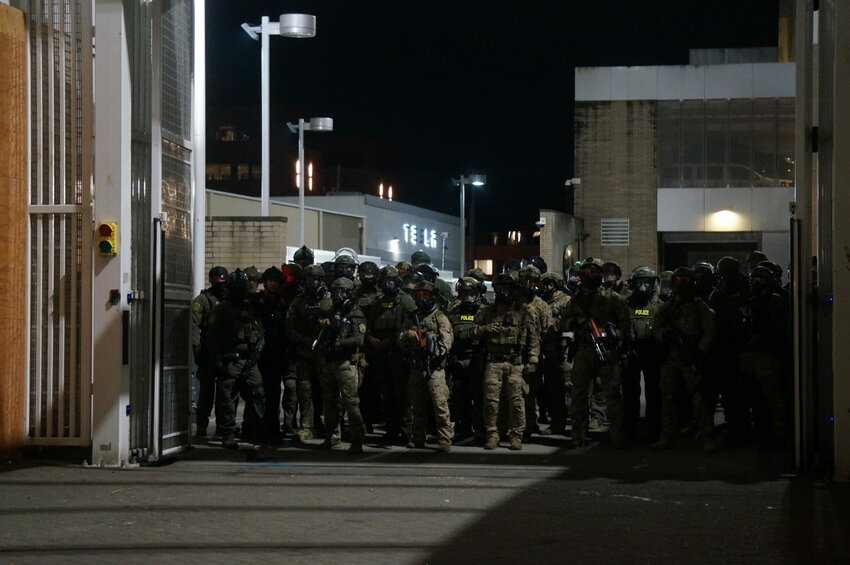 Federal police wait inside the gate of the Immigration and Customs Enforcement processing center south of downtown Portland during protests on Sunday, Oct. 6, 2025. (Photo by Alex Baumhardt)