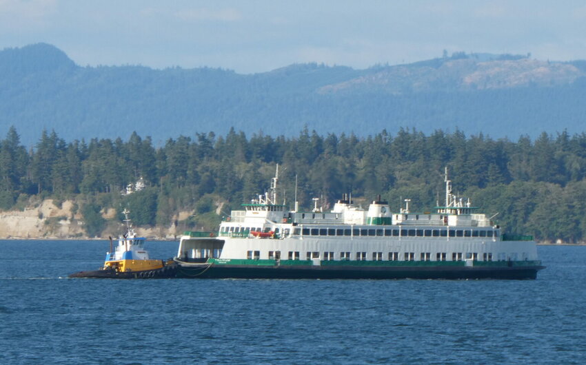 Washington State Ferries will need to keep its oldest ferries running for at least five more years before relief arrives. Shown here is the 66-year-old Tillikum being pushed by a tug after a summer breakdown. (Photo by Tom Banse)