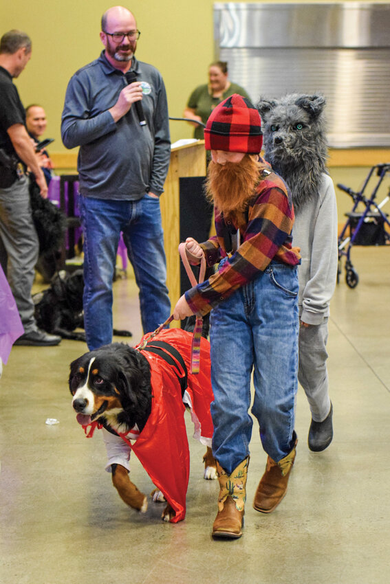 Denali, dressed as Little Red Riding Hood, walks the runway alongside owners costumed as the lumberjack and the Big Bad Wolf during the Howl-o-Ween Pooch Parade on Oct. 15. Families and pets filled the Battle Ground Event Center for the annual Halloween celebration.
