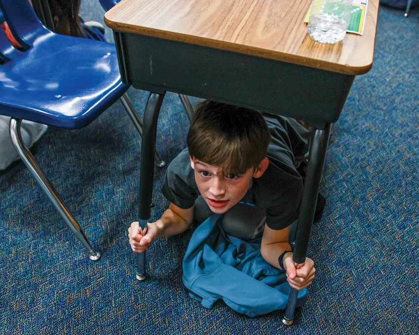 Kaden, a fourth-grade student in Eric Anderson&rsquo;s class at Maple Grove Elementary School in the Battle Ground Public Schools District, practices earthquake preparedness during the Great ShakeOut Drill on Thursday, Oct. 16.