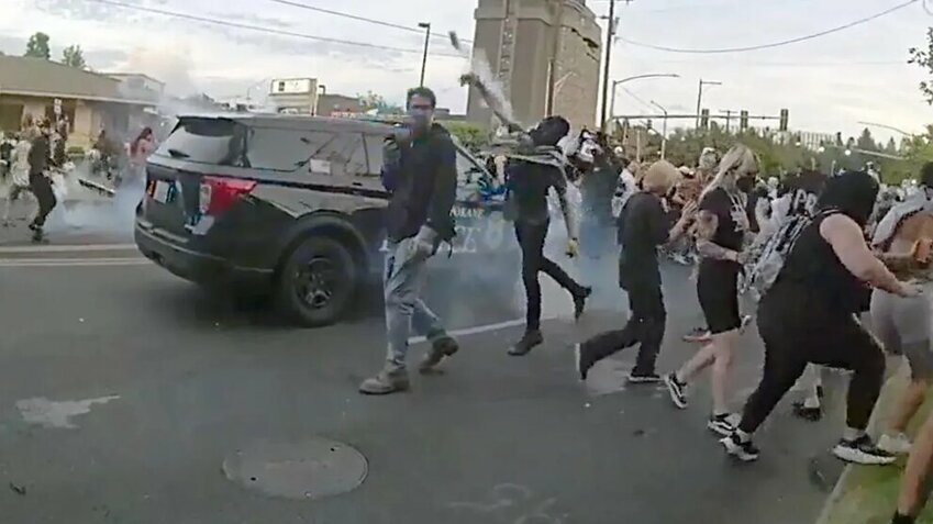 A protester throws a smoke canister back toward Spokane police officers and sheriff&rsquo;s deputies during a demonstration.